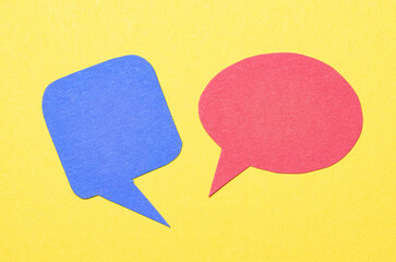 Red blue blank cut out paper speech bubbles with copy space for text on yellow background, flat lay...