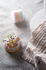 crafting scene with multicolored pins in pincushion, thread spools, and fabric with blue stitching on textured surface, tailor, strings, patterned, embroidery, workspace, threads, needlework