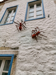 White Stone Wall with Red Ant Sculptures and Blue Window Frames