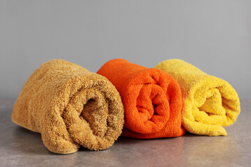 Rolled colorful towels on grey table, closeup