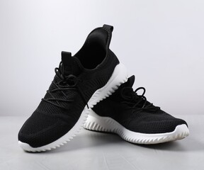 Pair of black sneakers on light grey surface
