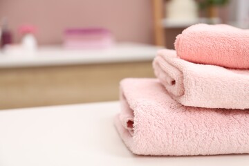 Stack of colorful towels on white table in bathroom, closeup. Space for text