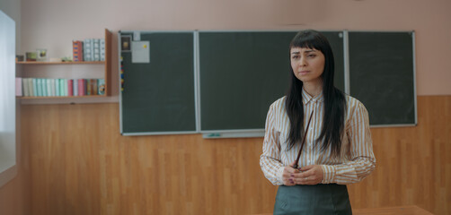 Portrait of a young teacher at the blackboard at school