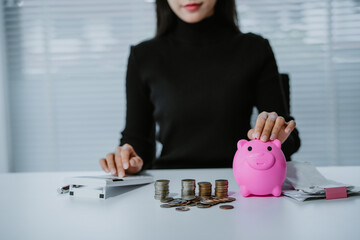 Positive attitude young Asian freelance businesswoman saving money for future, putting coins into...