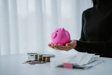 Positive attitude young Asian freelance businesswoman saving money for future, putting coins into...