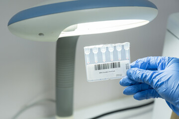 Doctor wear blue gloves holding coombs test card for cross matching blood bank analysis.Technician...