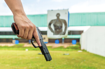 Police officer holding a law enforcement pistol in academy shooting range. Focus on gun right side view.