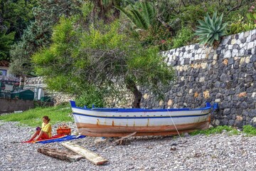 taormina, italien - ein frau liest am steinstrand liest ein buch