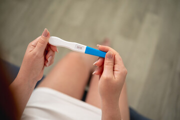A woman holds a pregnancy test with two stripes in her hands