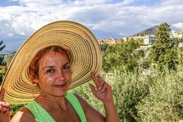 taormina, italien - eine frau mit sonnenhut blickt lächelnd in die kamera