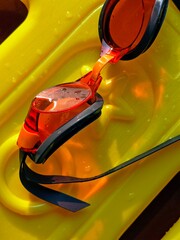 Wet Orange Swim Goggles on Bright Yellow Kickboard, Close-Up Detail