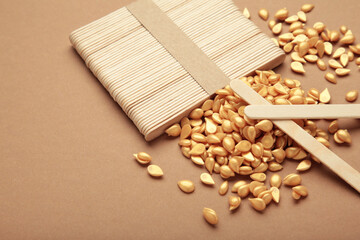 Beautiful gold depilatory wax granules and wooden spatulas on brown background. Epilation,...