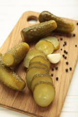 Marinated pickled cucumber on cutting board on white background. Vertical photo