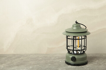 Hand holding lantern lamp on light background. Camping
