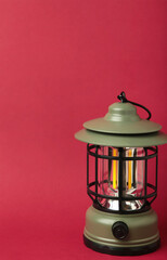 One lantern lamp on red background. Camping. Vertical photo