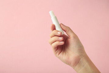 Female hand with natural lip balm on pink background