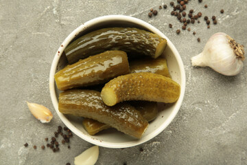 Marinated pickled cucumber with garlic on grey background.