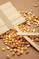 Beautiful gold depilatory wax granules and wooden spatulas on brown background. Epilation, depilation, unwanted hair removal.
