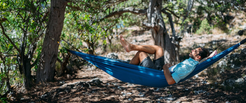 A man in a hammock on a hike in the mountains.