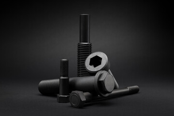 Variety of large black steel screws on black background.
