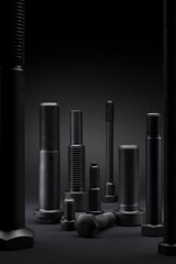 Variety of large black steel screws on black background.