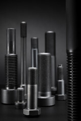 Variety of large black steel screws on black background.