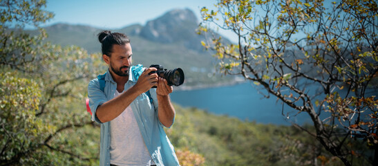Male tourist, photographer in a mountain grove overlooking the sea