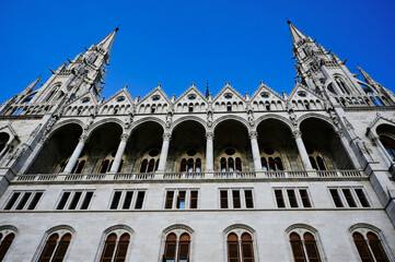elevation detail of the neo gothic stone parliament building in budapest along the danube river. arched windows. tall tower with turrets. famous historic landmark building. popular tourist destination