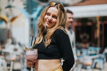 A young woman in fashionable attire is holding a colorful drink while enjoying good company at an...