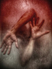 A man behind wet glass, hands pressed against it, expressing emotional pain.