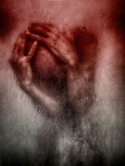 A man behind wet glass, hands pressed against it, expressing emotional pain.