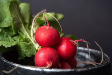 Fresh Red Radishes With Green Leaves In A Dark Bowl On Black Background