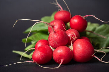 Two Bunches Of Fresh Red Radishes With Leaves On A Black Background
