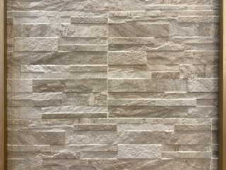 Close up of brown beige rectangular stone tiles combined with vertical gold frame trimming....
