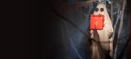 Halloween ghost holding gift box positive happy expression in darkness room with many spiderweb....