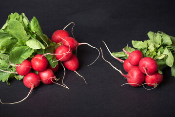Two Bunches Of Fresh Red Radishes With Leaves On A Black Background