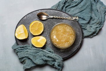 Spoon And Lemon Halves Next To A Jar Of Preserved Lemon On Gray Plate