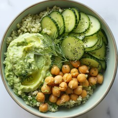 A refreshing bowl filled with quinoa cucumber chickpeas and a creamy avocado dressing topped with a sprinkle of dill.