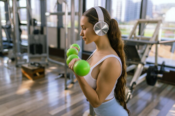 Attractive young woman working out with dumbbells at a gym.
