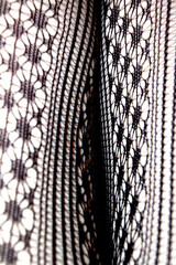 Close up of black lace fishnet tights on skin legs curves abstract background
