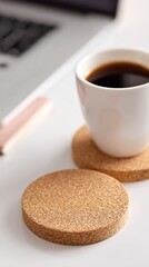 Coffee cup and cork coasters on white surface