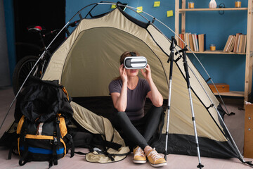 female tourist sitting in camping tent with virtual glasses preparing for trip at home.