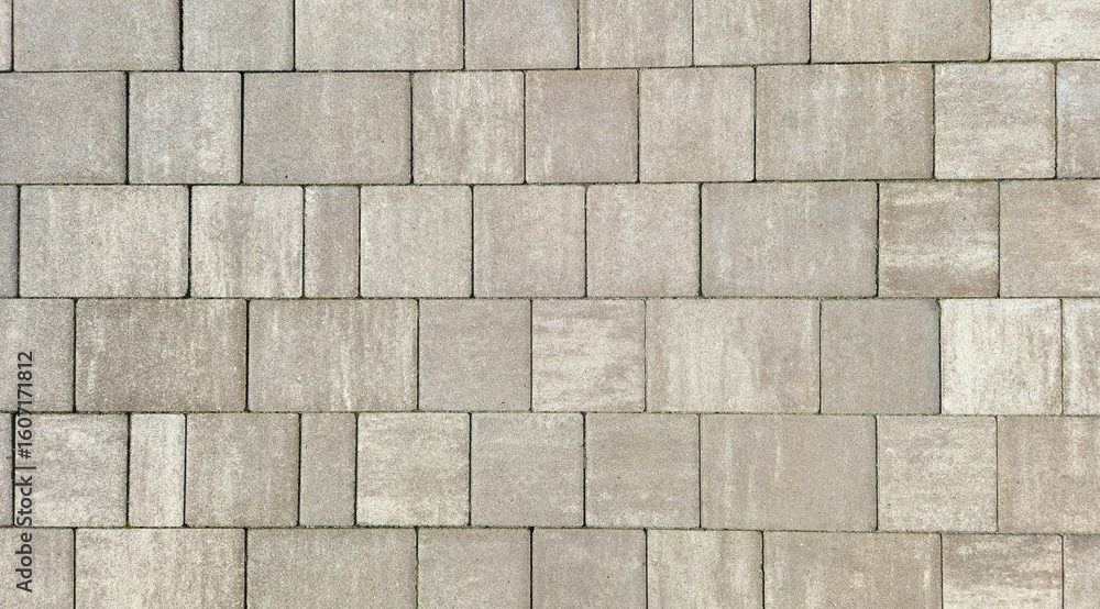 Poster close-up view of a textured pavement made of gray concrete blocks, showcasing a pattern that can be 