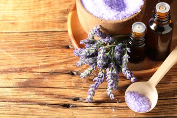 Plakat Bottles of lavender essential oil, sea salt and flowers on wooden table, above view. Space for text