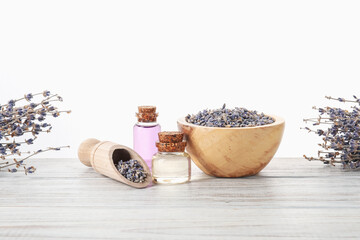 Natural essential oil and lavender flowers on wooden table against white background