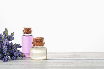Natural essential oil and lavender flowers on wooden table against white background
