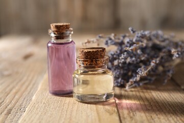 Natural essential oil and lavender flowers on wooden table, closeup