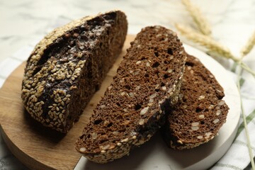 Pieces of fresh rye bread with seeds and spikes on table, closeup