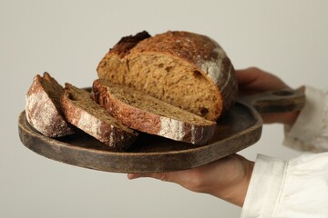 Woman with pieces of fresh bread on grey background, closeup