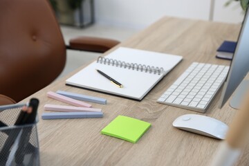 Modern computer and stationery on wooden desk in office, closeup. Comfortable workplace